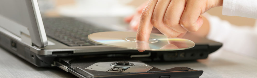 A CD getting placed in the drive of a laptop computer
